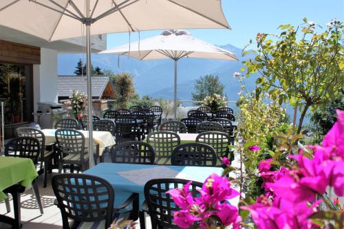 a patio with tables and chairs with pink flowers at La Cordée in Ovronnaz