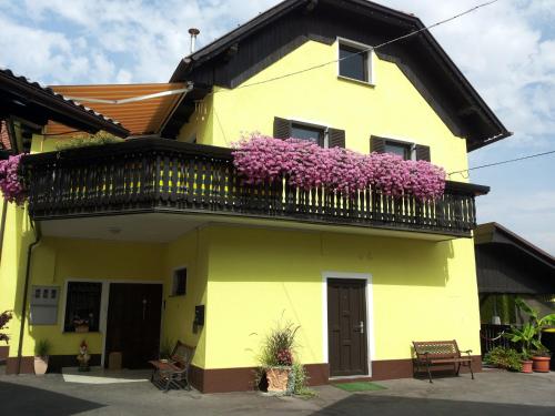 a yellow house with purple flowers on a balcony at Prenočišča Kralj in Komenda