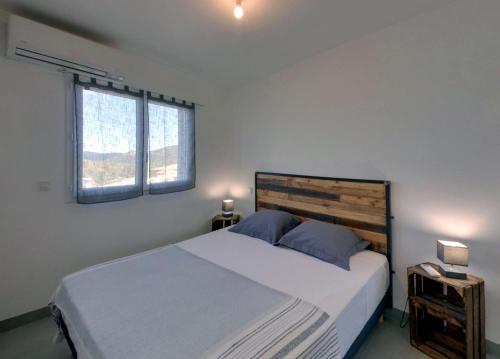 une chambre avec un grand lit et deux fenêtres dans l'établissement Villa Orethaga appart Ghjallu, à Porto-Vecchio