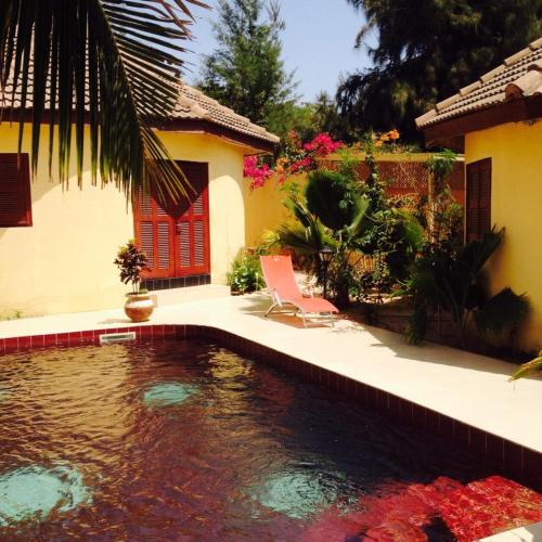 a swimming pool in a yard next to a house at Maison Couleur Passion in Nianing