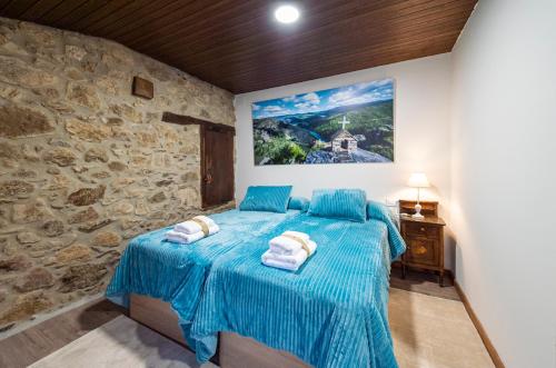 - une chambre avec un lit bleu dans un mur en pierre dans l'établissement Casa Pion, à Sober
