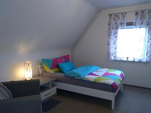 Un dormitorio con una cama con almohadas de colores y una ventana en Scharfs Kämmerla, en Baiersdorf