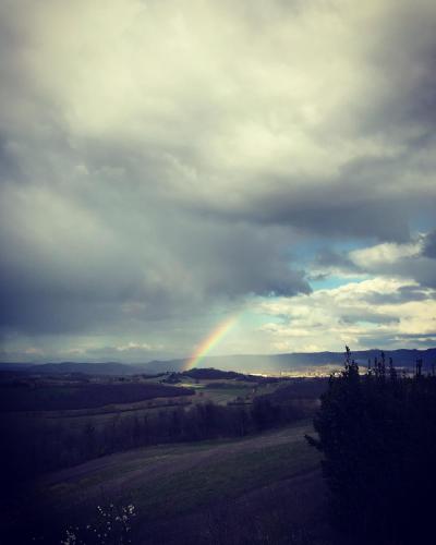 a rainbow in a cloudy sky with a field at Agriturismo Spazzavento in Palazzone