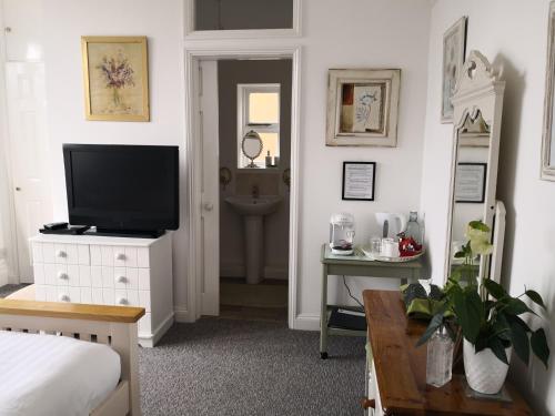 a bedroom with a bed and a television on a dresser at Sunset Guest House in Hunstanton