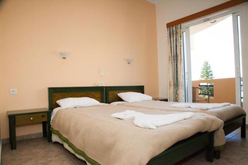 two beds in a room with a window at Meandros in Almirida