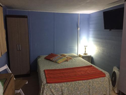 a bedroom with a bed and a tv on the wall at HansAna Blue in Barra de Valizas