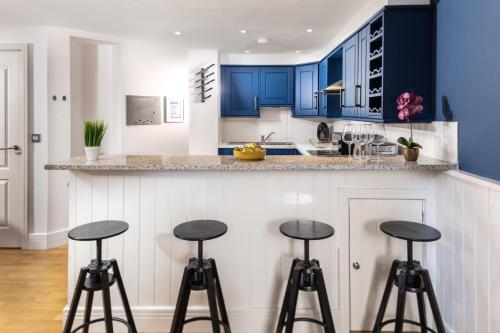 a kitchen with blue cabinets and bar stools at Plymouth Central Duplex Apartment - Private Parking - Sleeps 6 - Habita Property in Plymouth