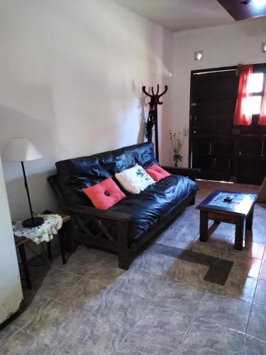 un sofá de cuero negro en una sala de estar con mesa en el Apartamento económico de Villa Gesell