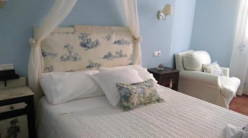 a bedroom with a white bed and a chair at La Casa del Telar in Valverde del Fresno