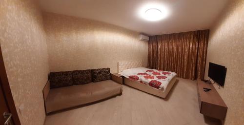 um pequeno quarto com uma cama e uma televisão em Просторные апартаменты Бариса Гмыри 14б em Kiev
