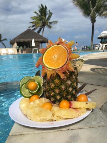 um ananás num prato ao lado de uma piscina em Beach Class Muro Alto Resort - flats e bangalôs em Porto de Galinhas