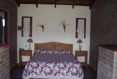 1 dormitorio con 1 cama, 2 mesas y 2 espejos en Los Almendros en La Cumbre