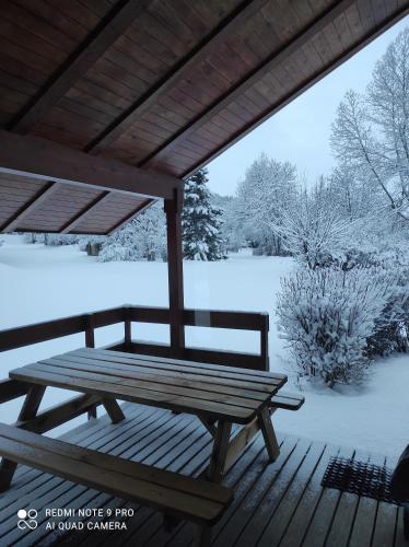 a picnic table and bench on a deck in the snow at Chalet calme in Saint-Léger-les-Mélèzes