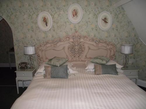 a bedroom with a large white bed with two lamps at Maenan Abbey Hotel in Llanrwst