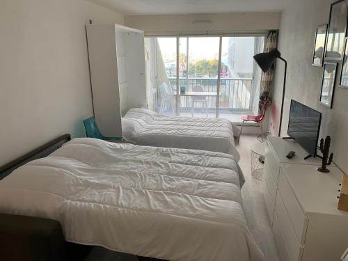 ラ・グランド・モットにあるStudio sur le portのバルコニー付きの客室内のベッド3台