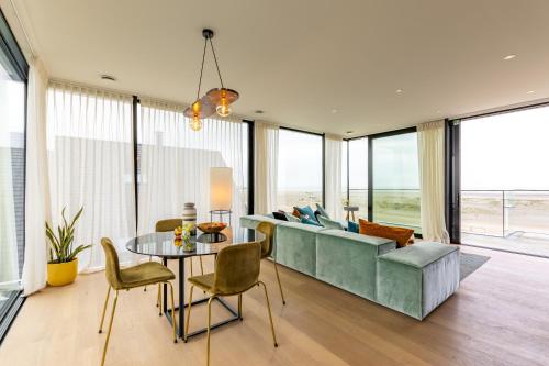 a living room with a couch and a table and chairs at Penthouse La Naturale zeezicht in Zeebrugge