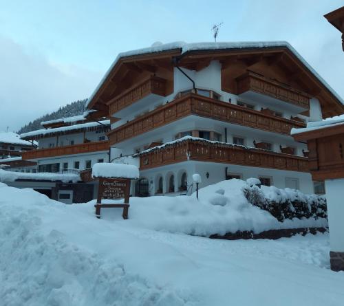 a building covered in snow with a sign in front at Garni Franca b&b in Selva di Val Gardena