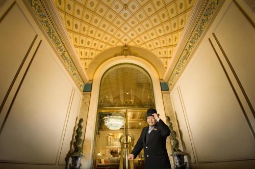 een man in een pak en hoed die voor een gebouw staat bij Mayflower Park Hotel in Seattle