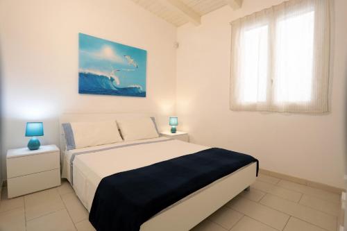 a white bedroom with a bed and a window at Casa Canoa - Le chiavi degli Iblei in Punta Braccetto