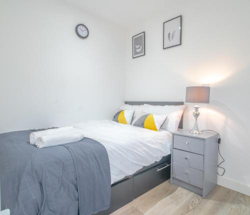 a white bedroom with a bed and a night stand at Modern Studio Apartments Sheffield City Centre - Netflix, WiFi, Digital TV in Sheffield