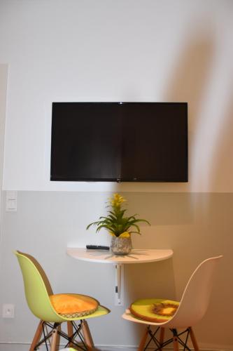 twee stoelen en een tafel met een tv aan de muur bij Appartement du Rhin in Neuhaeusel