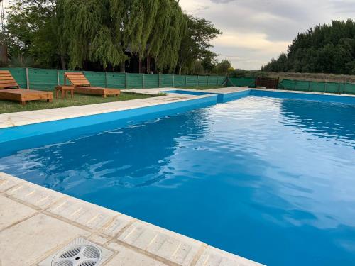 a swimming pool with blue water and two chairs at Complejo Cabañas Cerro Redondo in Tandil