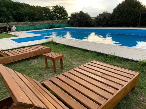 een zwembad met een houten bank en een tafel ernaast bij Complejo Cabañas Cerro Redondo in Tandil