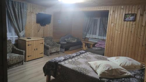 a bedroom with a bed and a chair and a tv at Sadyba Geredzhuka in Vorokhta