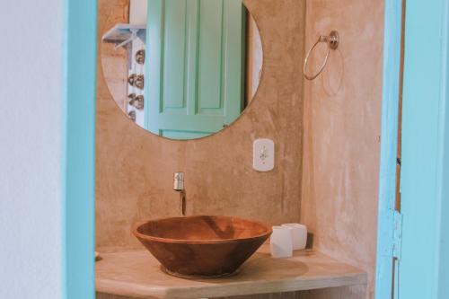 a bathroom with a wooden bowl sink in front of a mirror at Pousada Lua Cheia Caraíva in Caraíva