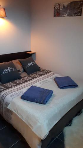 ein Bett mit blauen Kissen darüber in der Unterkunft Duplex 6-8 pers, avec garage, WIFI, calme, proche des pistes, top équipé et linges fournis, vue magnifique in Saint-Gervais-les-Bains