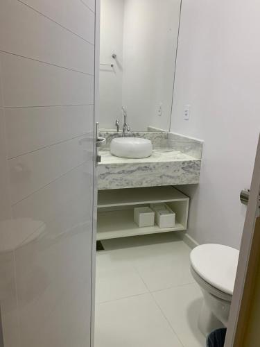 a white bathroom with a sink and a toilet at Suite Starfish in Guarujá
