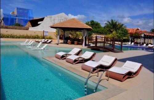 a swimming pool with lounge chairs and a gazebo at Barra Bali Apartamento 06 - Paraíso à Beira Mar in Barra de São Miguel