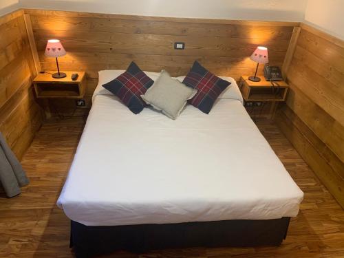 a large bed in a room with two lamps at Hotel Coeur Du Village in La Thuile
