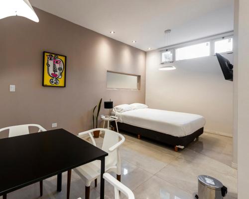 een slaapkamer met een bed en een tafel en stoelen bij Studio 25 de Mayo - San Luis in San Luis