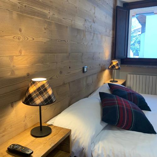 a bedroom with a bed with a wooden wall at Hotel Coeur Du Village in La Thuile