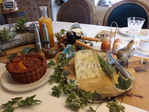 a table with a cutting board with cheese and vegetables at Maison des Quatre Saisons in Les Esseintes