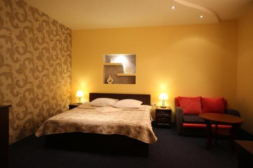 a hotel room with a bed and a chair at Złote Arkady in Częstochowa