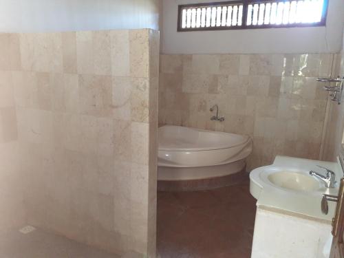 a bathroom with a tub and a toilet and a sink at Double One Villas in Amed