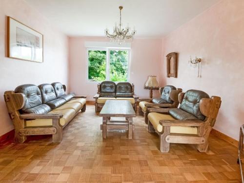 una sala de estar con muebles de cuero y una lámpara de araña. en Villa is approx 100 metres from the Atlantic en Le Pouldu