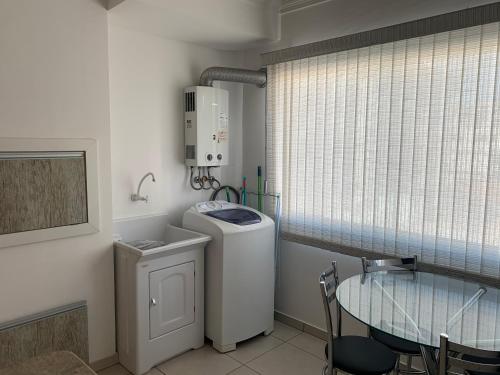 a washing machine in a room with a glass table at Lindo apartamento mobiliado in Capão da Canoa