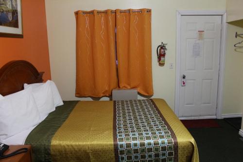 a bedroom with a bed and a window with an orange curtain at Norvic Motel in Coniston