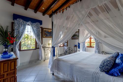 a bedroom with a white bed with a canopy at Suites La Hacienda in Puerto Escondido