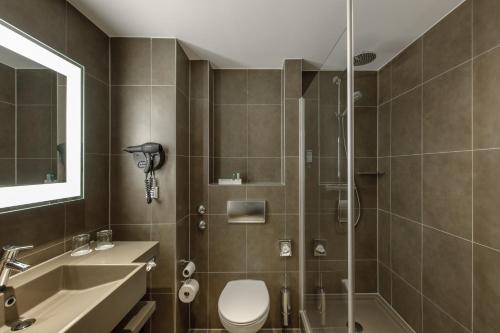 a bathroom with a toilet a sink and a bathtub at Novotel Hannover in Hannover