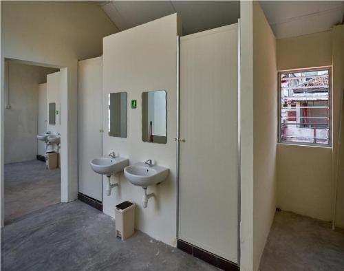 La salle de bains est pourvue de 2 lavabos et de 2 miroirs. dans l'établissement We Love GuestHouse, à George Town