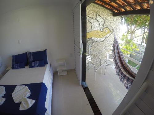 a bedroom with a bed and a balcony with a painting at Chalé 4, Maragogi, Condominio Village Galés in Maragogi