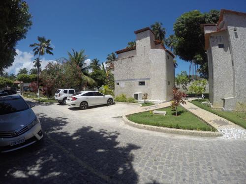 a building with two cars parked in a driveway at Chalé 4, Maragogi, Condominio Village Galés in Maragogi