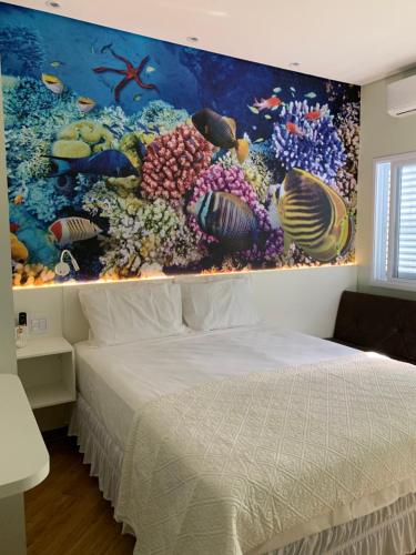 a bedroom with a bed with a painting on the wall at Suite Aquarius in Guarujá
