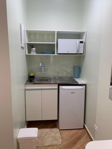 uma pequena cozinha com um lavatório e um micro-ondas em Suite Aquarius no Guarujá