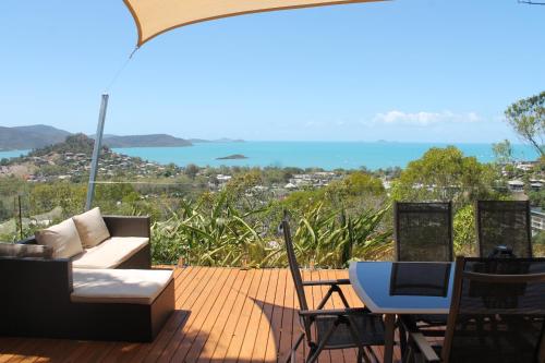 a deck with a couch and a table and chairs at Yachtsmans Paradise, Whitsundays in Airlie Beach