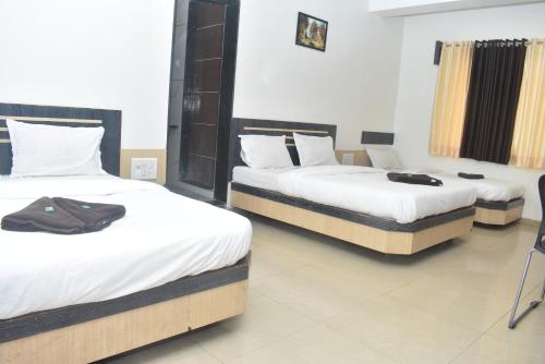 three beds in a room with white sheets at HOTEL SAI VISHVA KARMA in Shirdi